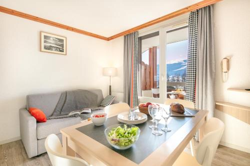 un salon avec une table, des chaises et un canapé dans l'établissement Résidence Pierre & Vacances Les Bergers, à L'Alpe-d'Huez