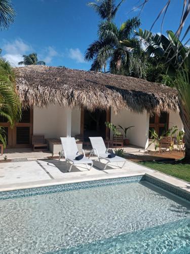 a resort with a swimming pool and two chairs and a thatch hut at Casa Shambala B&B in Las Terrenas