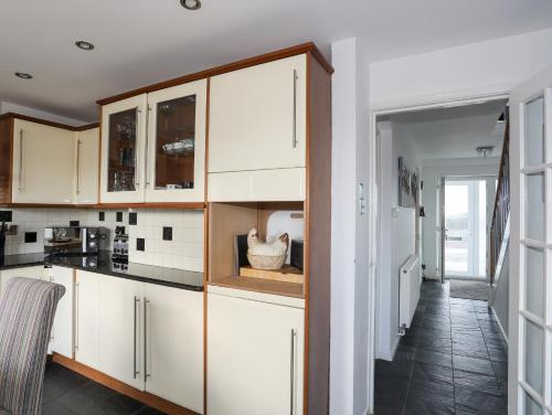 a kitchen with white cabinets and a hallway at 21 Min Y Mor in Pwllheli