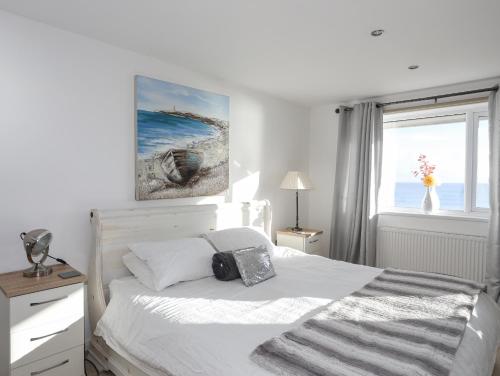 a white bedroom with a bed and a window at 21 Min Y Mor in Pwllheli
