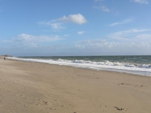 a beach with the ocean and a person walking on it at 21 Min Y Mor in Pwllheli