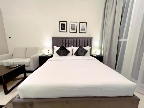 um quarto com uma grande cama branca e um sofá em Cozy Studio in Dubai no Dubai