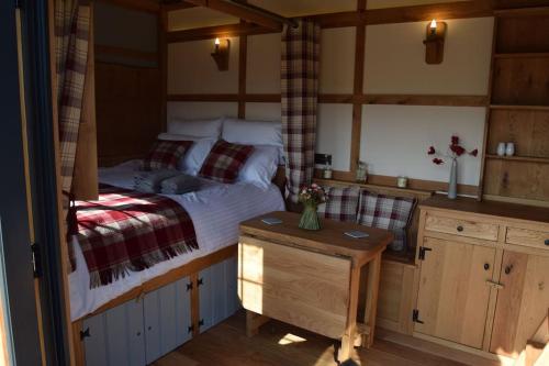 a bedroom with a large bed and a table at The Flying Scotsman Shepherd's Hut with Hot Tub in Brecon