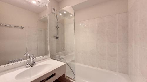 une salle de bain blanche avec une douche et un lavabo dans l'établissement Grand Cerf 78, à Saint-Jean-dʼAulps