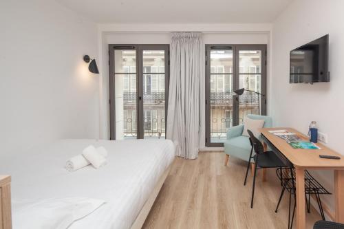 ein weißes Schlafzimmer mit einem Schreibtisch, einem Bett, einem Tisch und einem Stuhl in der Unterkunft FINESTATE Coliving Champs-Elysées in Paris