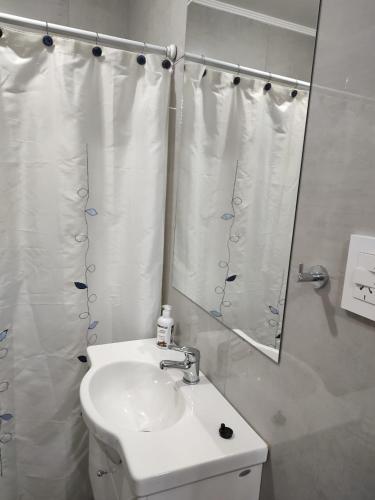 een witte badkamer met een wastafel en een spiegel bij La Plaza MONOAMBIENTE in Sunchales