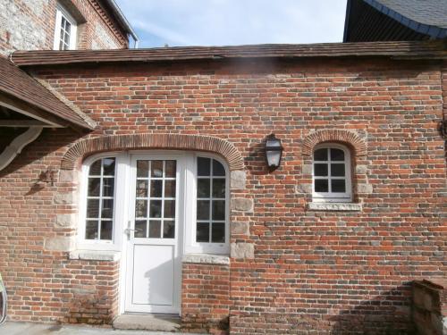 a brick building with a white door and windows at AU CLAIRE DE LUNE in Le Bourg-Dun