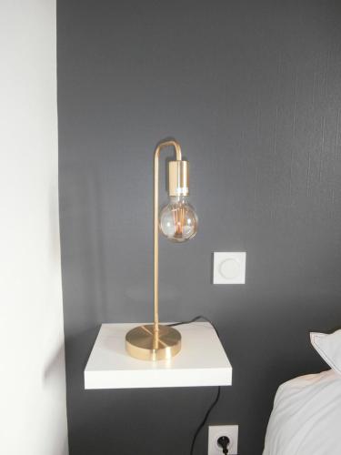 a lamp sitting on a table in a bedroom at AU CLAIRE DE LUNE in Le Bourg-Dun