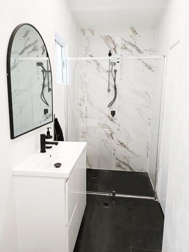 a white bathroom with a shower and a sink at Stunning Queen Room 1Min Walk to Station with 55 Inch TV in Sydney