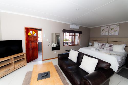 a bedroom with a bed and a couch and a tv at Kleinplasie Guesthouse in Springbok