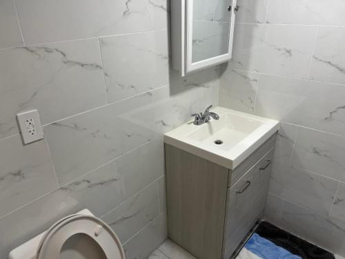 bagno bianco con lavandino e servizi igienici di Single Room a Elmont