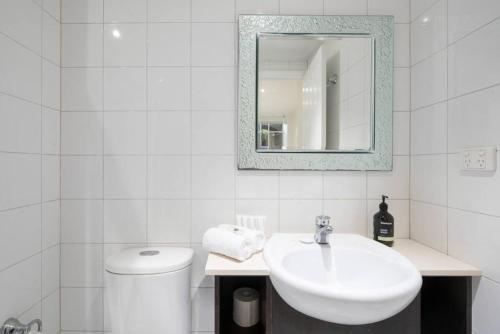 Baño blanco con lavabo y aseo en Gordons Place Entire Apartment CBD Location, en Melbourne