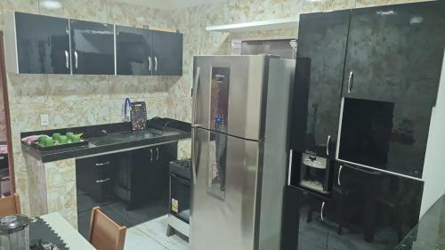 d'une cuisine équipée d'un réfrigérateur en acier inoxydable et de placards noirs. dans l'établissement Flat Recanto da Natureza 02, à Cabo de Santo Agostinho