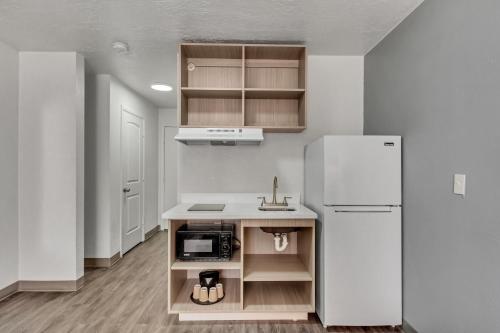 a kitchen with a white refrigerator and a sink at Suburban Studios Salt Lake City Airport in Salt Lake City