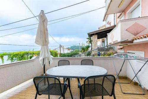 a table and chairs on a balcony with an umbrella at Apartments Antonija in Kampor