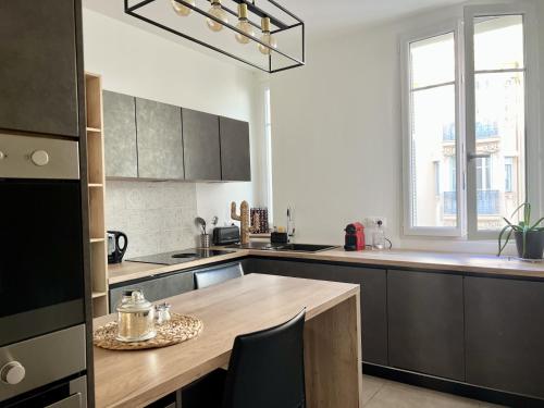 une cuisine avec une table en bois et une grande fenêtre dans l'établissement Luxueux Appartement 115m2, 3 Chambres centre ville avec parking à 5 min plage -climatisation, à Nice