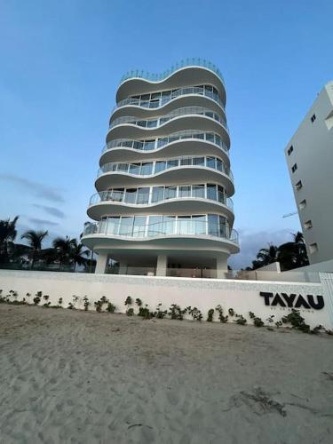 a tall building on the beach next to the sand at Departamento Costa Dorada, Bucerias Beach Front in Bucerías