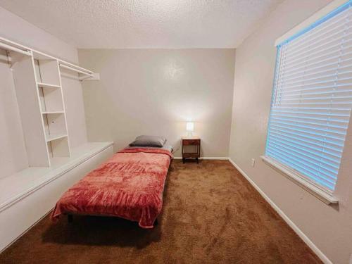 a bedroom with a bed with a red blanket and a window at Workforce Ready 2 bedroom Home in Corpus Christi