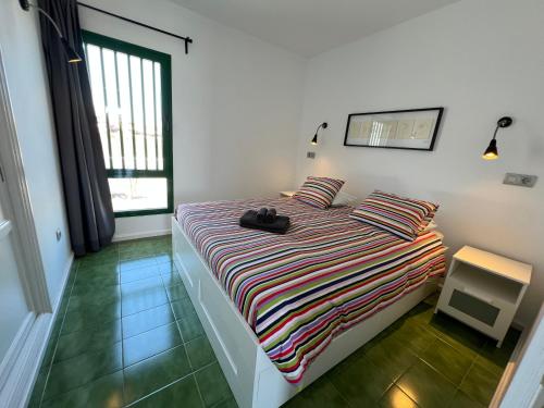 a bedroom with a bed with a striped blanket at Casa Luna in Puerto del Carmen