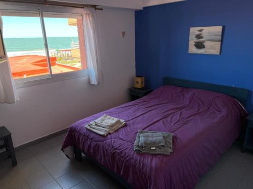 Un dormitorio con una cama con sábanas moradas y una ventana al Departamento Libra XX Frente al mar!Promo primavera en Villa Gesell