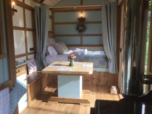 a small room with a table and a couch at The Mallard Shepherd's Hut with Hot Tub in Brecon
