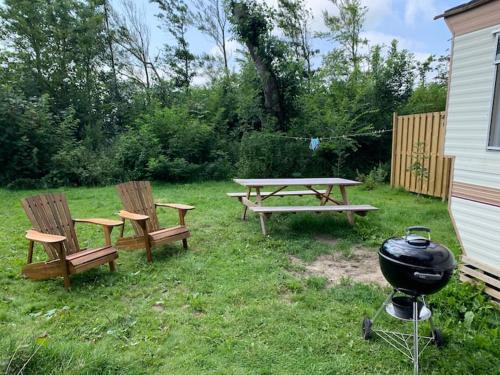 Duas cadeiras, uma mesa de piquenique e um grelhador num quintal em Stacaravan met tuin aan de Waddenzee em Oosterend