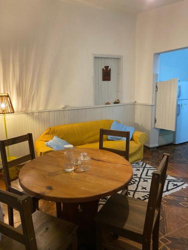 a living room with a table and a yellow couch at Casa de 1 Dormitorio ubicado en planta baja. A 150 mts de la playa en La Aguada y Costa Azul, La Paloma, Rocha in Costa Azul