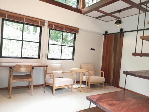 Zimmer mit einem Tisch, Stühlen und Fenstern in der Unterkunft The Reef Hotel & Studios in Ko Lipe