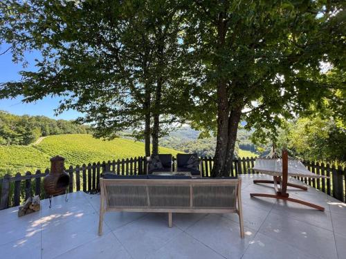 a patio with a bench and a table and a tree at House-tanjevica in Kostanjevica na Krki