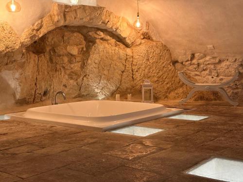 a bath tub in a stone room with a chair at Arquati Suite Luxury Apartment in Ostuni