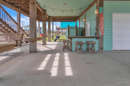 a porch with a table and stools on a house at Steps to beach Golf Cart About Time Beach Retreat in Bolivar Peninsula