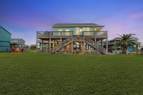 a large house with a deck on a grass field at Steps to beach Golf Cart About Time Beach Retreat in Bolivar Peninsula