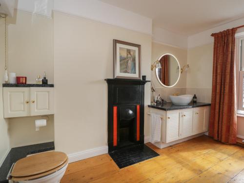 uma casa de banho com uma lareira preta e um lavatório em The Gate House em Cirencester
