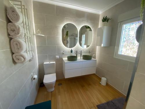 ein Bad mit einem Waschbecken, einem WC und Spiegeln in der Unterkunft Villa Benjamina avec piscine climatisée in Altea