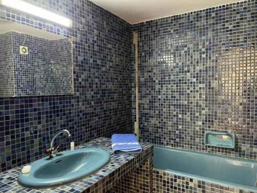 baño de azulejos azules con lavabo y bañera en MODERNE APPART PLEIN CENTRE, en Fez