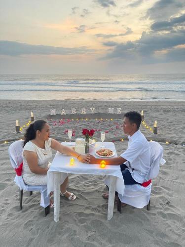 un hombre y una mujer sentados en una mesa en la playa en Palapa Abraham, 