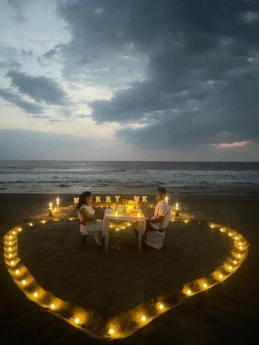 dos personas sentadas en una mesa en un corazón en la playa en Palapa Abraham, 