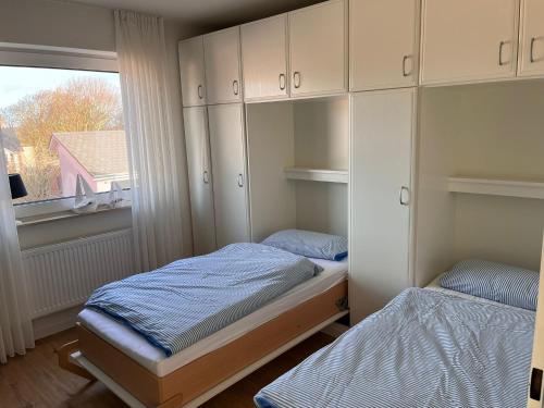 ein kleines Schlafzimmer mit 2 Betten und einem Fenster in der Unterkunft Ferienwohnung Antje auf Borkum in Borkum