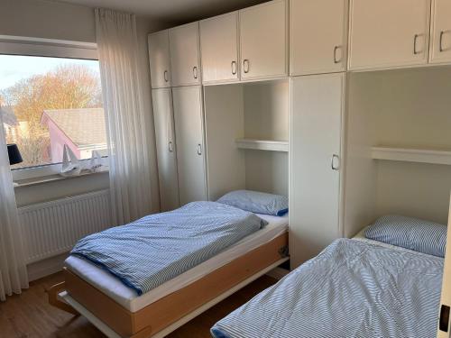 una piccola camera da letto con due letti e una finestra di Ferienwohnung Antje auf Borkum a Borkum