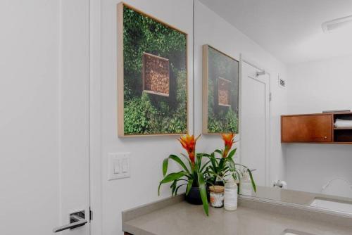 a bathroom with two pictures on the wall and flowers on a counter at The Sunset Blvd luxury high-rise, 180 city views in Los Angeles