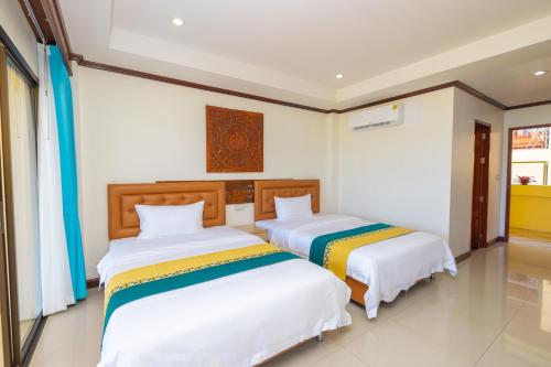 two beds in a room with white walls at Kana Hotel Phuket普吉岛卡娜酒店 in Rawai Beach