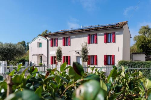 a white house with red shuttered windows at 5 min dal centro - Ca'Lea - Motta di Livenza in Motta di Livenza