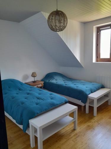 Duas camas num quarto branco com lençóis azuis em Gite Au Bout du Monde 