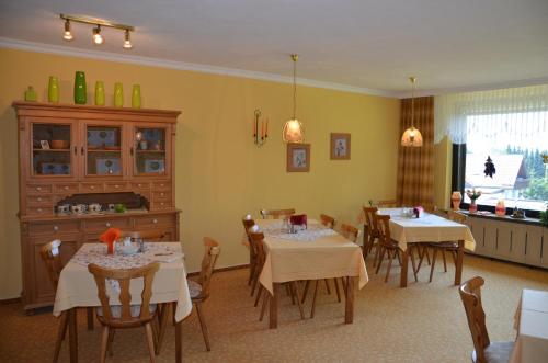 jadalnia ze stołami i krzesłami oraz kuchnia w obiekcie Pension Alfa w mieście Sankt Andreasberg