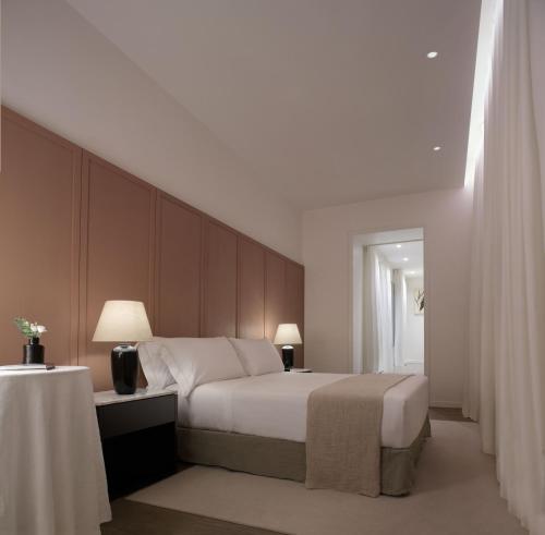 a bedroom with a bed and a table with two lamps at Parisii Bocca di Leone 88 in Rome