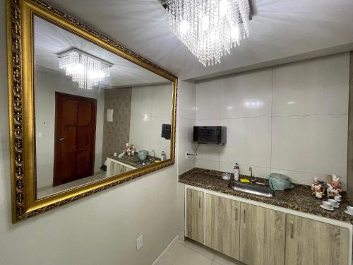 La salle de bains est pourvue d'un grand miroir et d'un lavabo. dans l'établissement The Férias | Suites Luxo, à Cabo Frio
