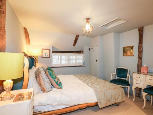 a bedroom with a bed and a desk and a chair at Peppermint Cottage in Petworth