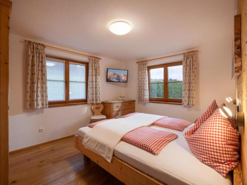 ein Schlafzimmer mit einem Bett und zwei Fenstern in der Unterkunft Apartment-Chalet Mödlinghof in Hopfgarten im Brixental