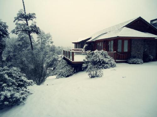 a house covered in snow in front of a house at Hosteria Patagon in Villa La Angostura