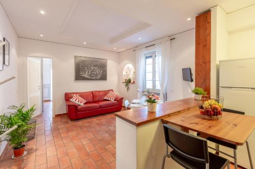 Milvio Bridge - cozy apartment in Rome في روما: مطبخ وغرفة معيشة مع أريكة حمراء